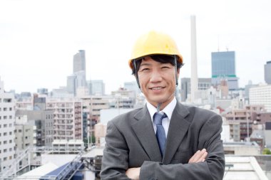 Güvenlik kaskı takmış gülümseyen bir iş adamı 