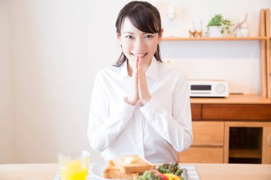 Asyalı kız portakal suyu ve tostla kahvaltı yapıyor.