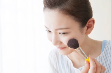 Makyaj fırçası süren Asyalı kadın.