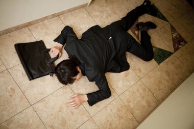 Genç işadamı yerde yatıyor.