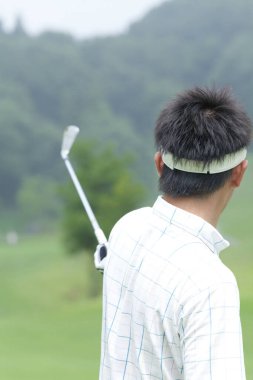 Genç Japon adam gündüz golf oynuyor. 