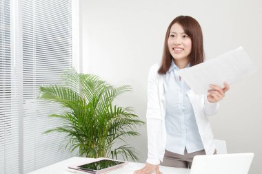 Ofiste elinde kağıt tutan genç bir kadın.