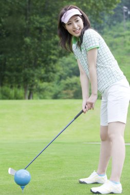 Yeşil çimlerin üzerinde golf oynayan kadın.