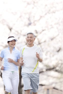 Asyalı olgun çift parkta koşuyor.