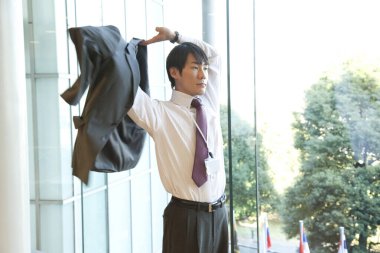 Ofiste duran işadamı ceketini giyiyor. 