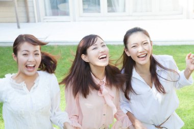 Üç kadın çimlerin üzerinde gülüyor.