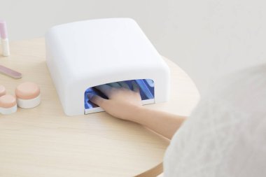 UV tırnak kurutma makinesi kullanan bir kadın.