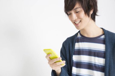 Genç Asyalı adam akıllı telefon kullanıyor, stüdyo fotoğrafı. 