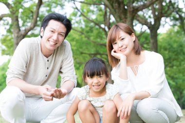 Genç anne baba ve kız parkta yerde oturuyorlar.