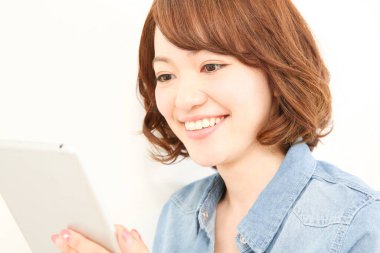 Dijital tablet kullanan gülümseyen Asyalı kadın