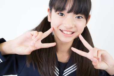 Beyaz stüdyo arka planında duran üniformalı Japon okul kızının portresi. 