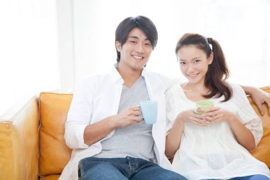 Genç çift kanepede kahve içerken dinleniyor.