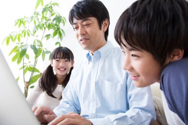 Oğlu ve kızı olan genç bir adam evde dizüstü bilgisayar kullanıyor.