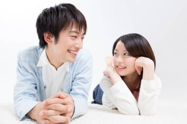 Genç bir çift yerde sırıtarak yatıyor.