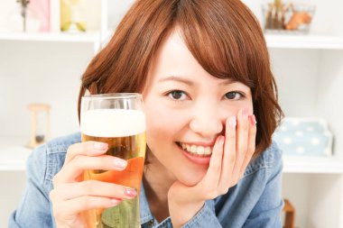 Neşeli Japon kadın evde bira içiyor.