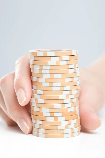 female hand with stack of casino chips, close up view