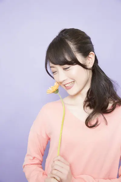 笑容满面的年轻亚洲女人 手持一朵鲜花 — 图库照片