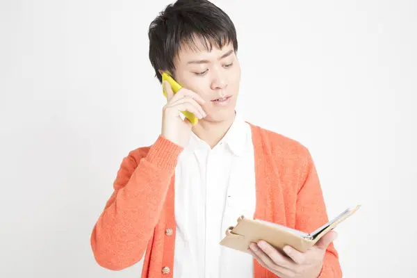 Asiático Hombre Rtalking Smartphone Buscando Notebook —  Fotos de Stock