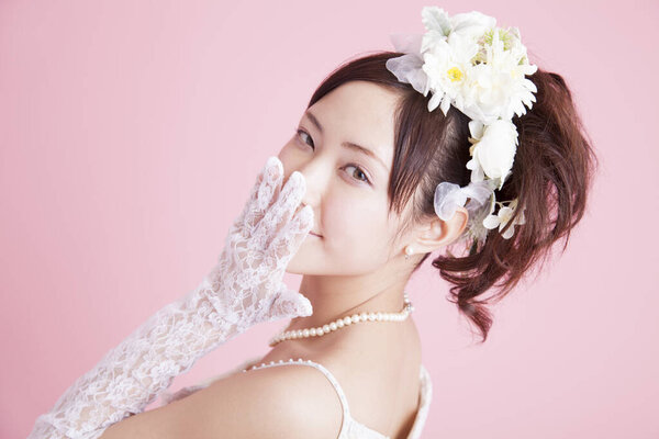 Beauty Japanese bride in wedding dress and accessories posing on white studio background