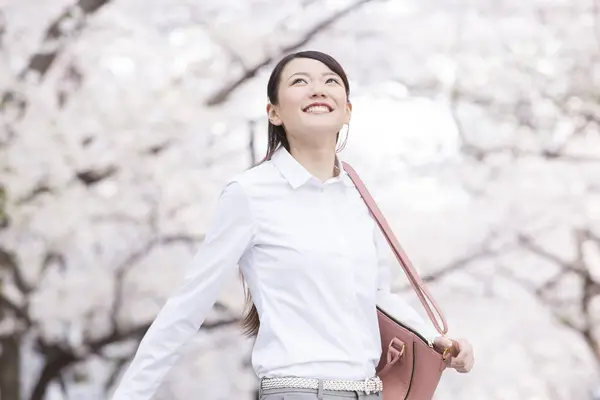 asian woman with cherry blossoms in park