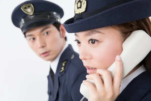 studio portrait of Japanese police officers answering phone call