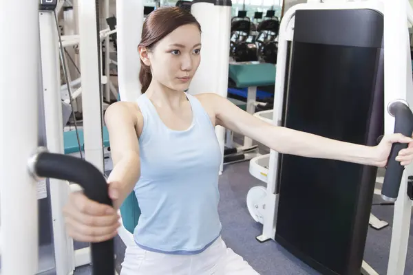 Kaunis Nuori Aasialainen Nainen Tekee Liikuntaa Kuntosalilla — kuvapankkivalokuva