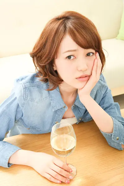 portrait of sad Asian woman drinking wine at home