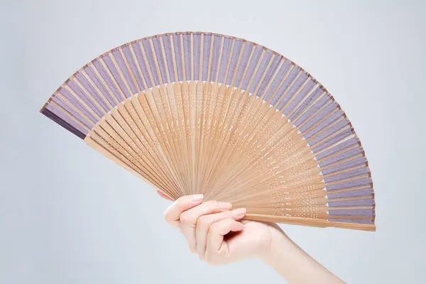 close up photo of woman holding fan in hand