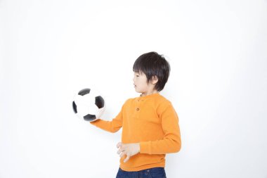 Asyalı çocuk futbol topuyla oynuyor.