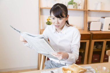 Asyalı kadın evde gazete okuyor. 