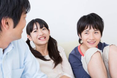 Genç Asyalı aile kanepede dinleniyor.