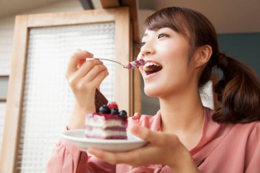 Mutlu Asyalı kadın pasta yiyor.