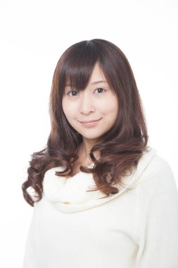 Beyaz arka planda beyaz kazaklı genç bir kadın.