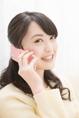 Akıllı telefondan konuşan gülümseyen Asyalı kadın, yakın plan portre 