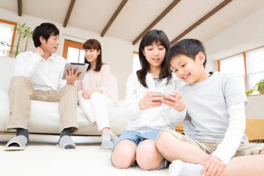 Oturma odasında alet kullanan dört kişilik genç bir aile. 