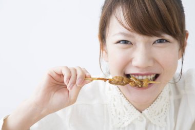 Kızarmış kebap yiyen Asyalı kadın.