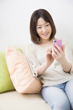 Oturma odasında akıllı telefon kullanan kadın.