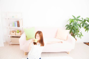 Kadın oturma odasında kahve içiyor. 