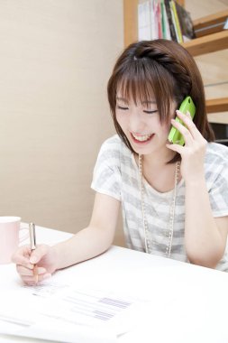 Genç Asyalı kadın tasarımcı telefonda konuşuyor.