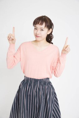 Beyaz arka planda parmaklarını gösteren Asyalı genç bir kadının portresi