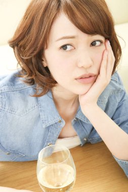 Evde şarap içen üzgün Asyalı kadının portresi.