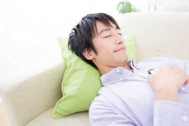 Akıllı telefonlu bir adam kanepede uyuyor. 