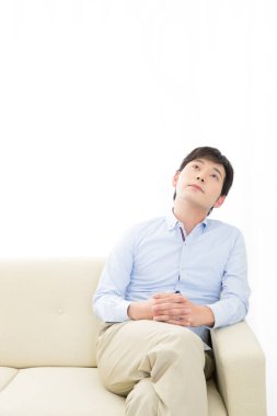 Genç Asyalı adam evde dinleniyor.