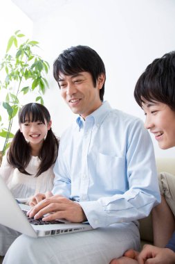 Oğlu ve kızı olan genç bir adam evde dizüstü bilgisayar kullanıyor.