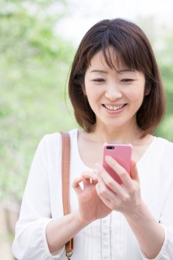 Açık havada cep telefonu kullanan Asyalı kadın.