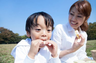 Neşeli Asyalı anne ve oğlu parkta piknik yapıyor.