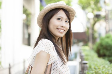 Güzel gülümseyen Asyalı kadın sokakta poz veriyor.