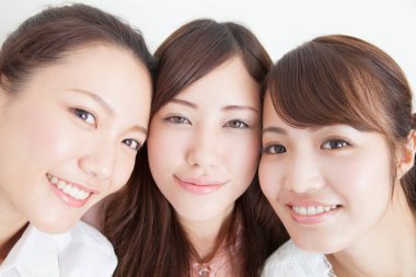 Üç gülümseyen genç Japon kadının portresi.
