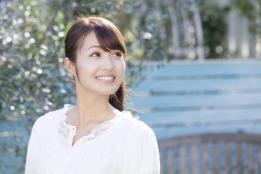 Parkta gülümseyen genç Asyalı kadın.