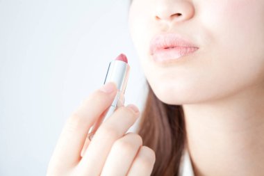 Ruj süren genç bir kadın, stüdyo fotoğrafı. 